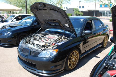2005 Subaru Impreza - A black Subaru Impreza WRX STI sedan is displayed with its hood open, revealing the engine bay.