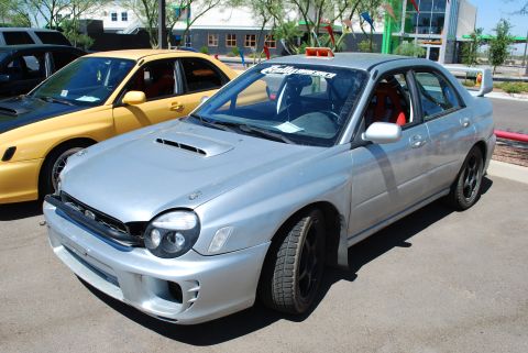 2005 Subaru Impreza - Silver 2005 Subaru Impreza WRX STI parked next to a yellow car at an auto show.