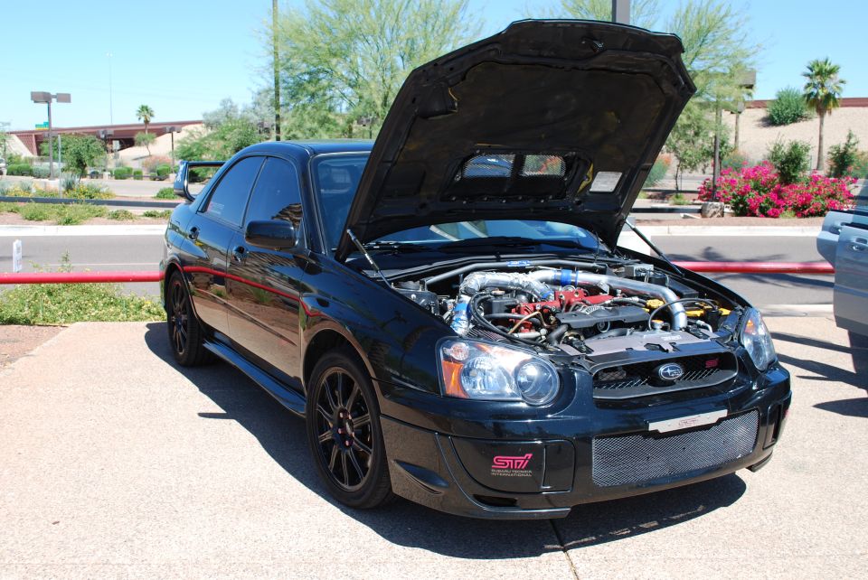 Black Subaru Impreza WRX STI with hood open, showing engine. Has 'STI' badge on front bumper