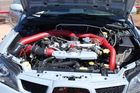 2005 Subaru Impreza - The engine bay of a 2005 Subaru Impreza features prominent red intake piping.