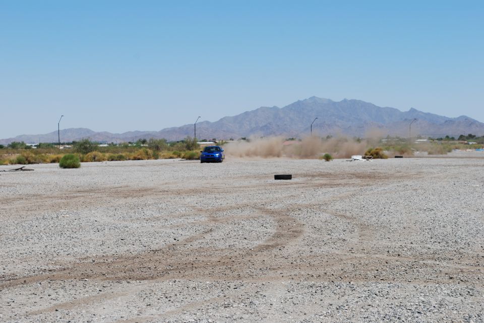 Blue Subaru Impreza kicking up dust on a gravel lot