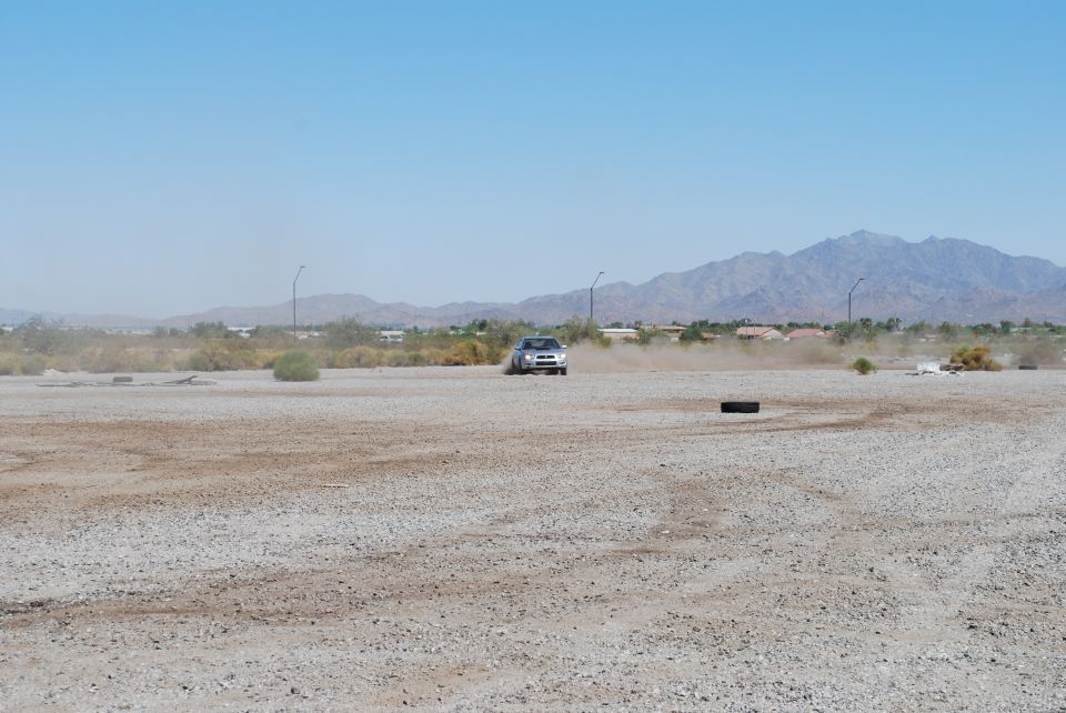 Silver 2005 Subaru Impreza driving on a dusty lot