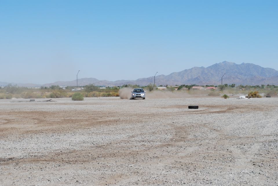 Silver 2005 Subaru Impreza driving on a dirt road, kicking up dust