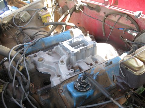 1978 Ford Bronco - Close-up view of an engine's intake manifold and carburetor assembly, with blue valve covers.