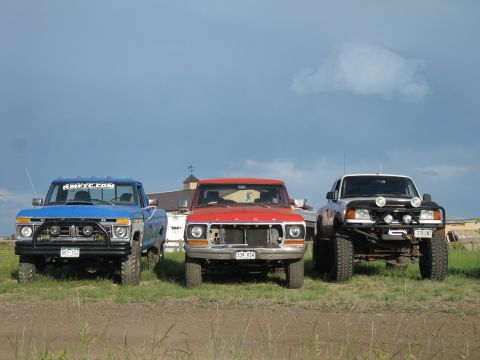 1978 Ford Bronco - Three trucks, including a blue 1970s Ford and a white Ford Ranger, are parked outdoors.