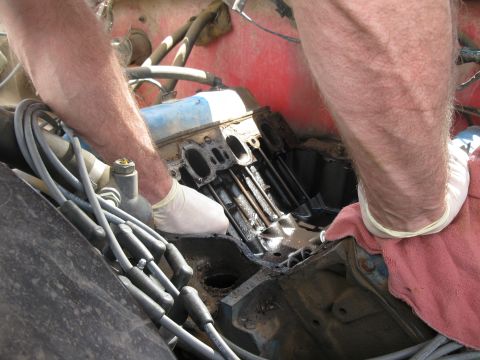 1978 Ford Bronco - Close-up of an engine bay with a person performing maintenance on the motor.