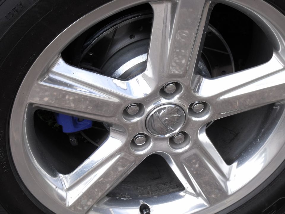 Close-up of a chrome five-spoke wheel with a blue brake caliper visible behind it