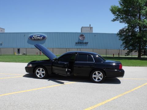 2003 Mercury Marauder - A black sedan sits in a parking lot with its hood and driver's door open, in front of a building displaying Ford and Mercury branding.