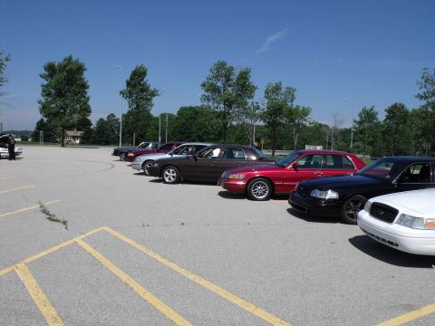 2003 Mercury Marauder - A line of sedans, including a red, black, and white model, are parked in a lot under a clear blue sky.