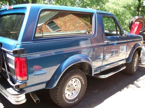 1995 Ford Bronco - This blue SUV is parked outdoors, showing its side profile with a spare tire carrier on the rear.