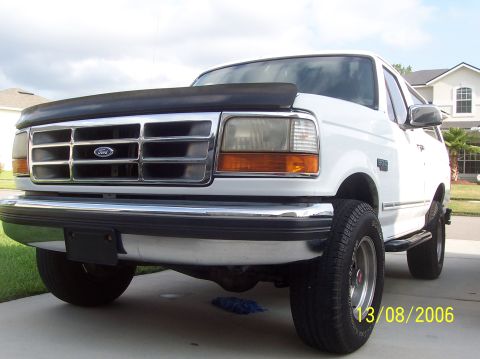 1994 Ford Bronco - Front three-quarter view of a white Ford Bronco with a black hood protector and chrome grille.
