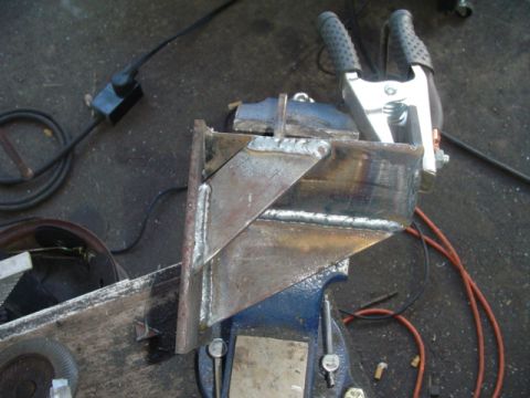1993 Ford Bronco - A custom metal bracket is being welded and secured in a vise, with welding cables nearby.