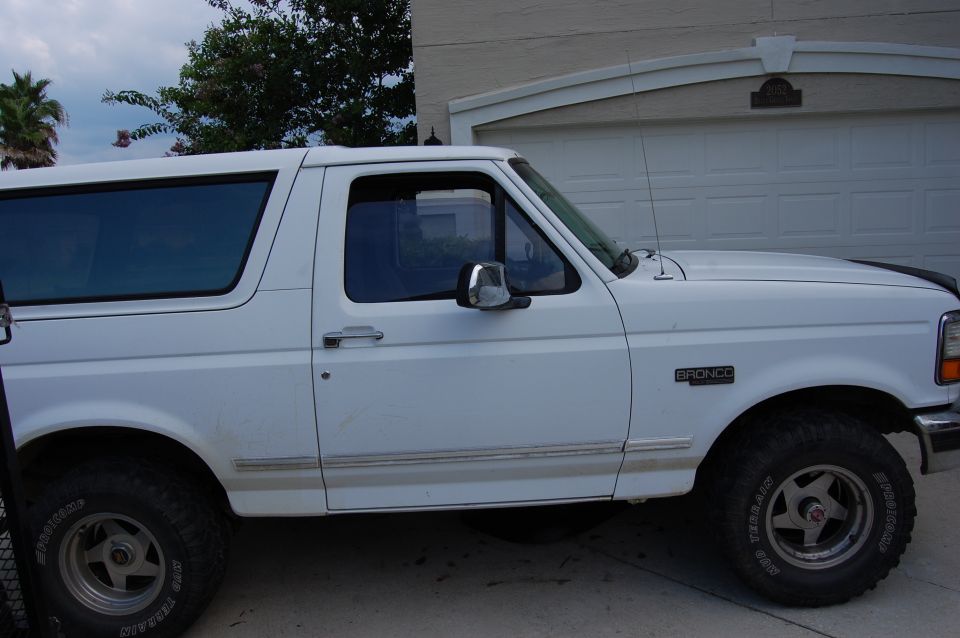 White 1994 Ford Bronco side view, parked in front of a garage