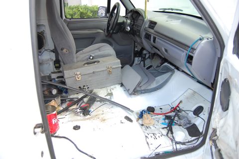 1994 Ford Bronco - The interior of a white truck shows a messy floor with tools and wiring visible wiring.