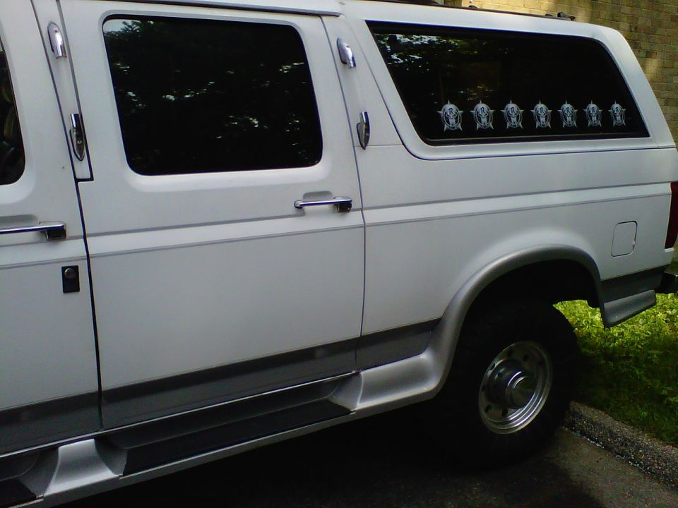 Side view of a white conversion van with tinted windows and chrome trim