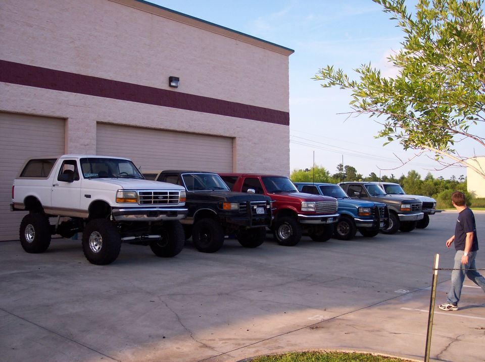 White lifted Ford Bronco with large tires parked in front of a building