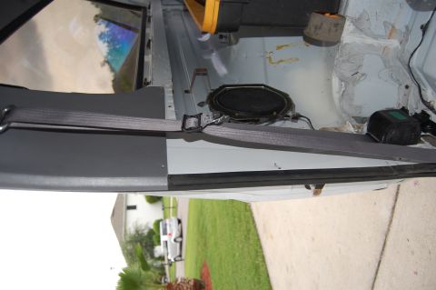 1994 Ford Bronco - The interior of the vehicle reveals a speaker and seatbelt, with a glimpse of the exterior through the window.