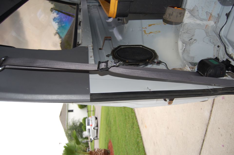 Interior view of a vehicle showing a speaker and seatbelt