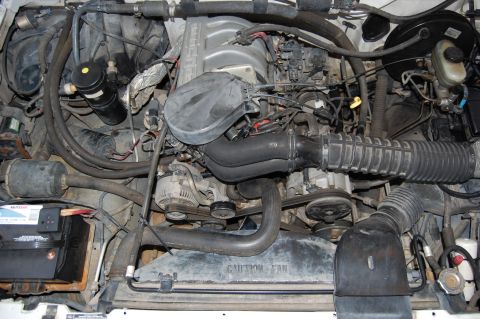 1994 Ford Bronco - The engine bay of a vehicle, showing various components and hoses. Text on the fan shroud is visible.