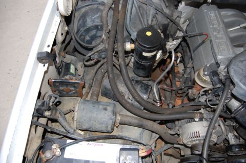 1994 Ford Bronco - Engine bay of a 1994 Ford Bronco, showing various components and a battery.