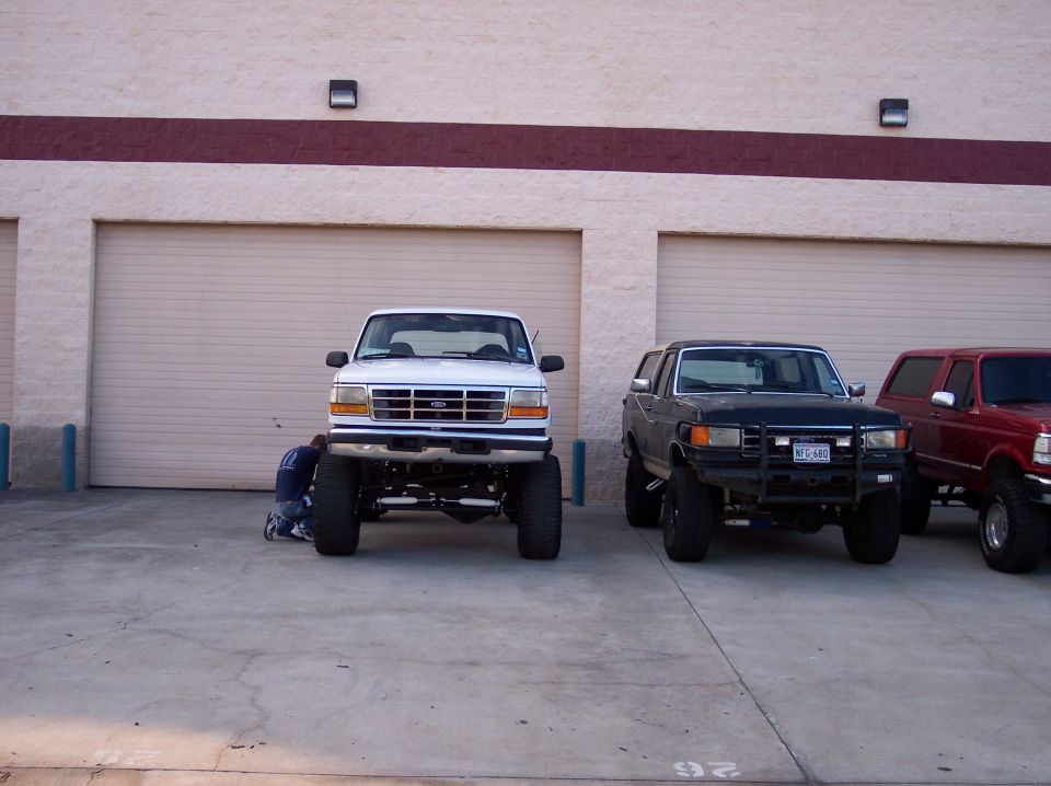 Lifted white Ford F-150 truck in front, black Ford Bronco in middle, red Ford Bronco in back