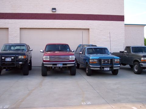 1995 Ford Bronco - A lineup of four trucks and an SUV, with the red truck a prominent aftermarket grille.