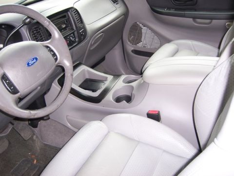 2007 Ford Mustang - The interior of a light-colored SUV is visible, the steering wheel, center console, and perforated seats.