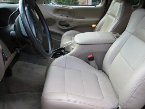 2007 Ford Mustang - The interior of a vehicle features tan leather seats and a center console with a cup holder.