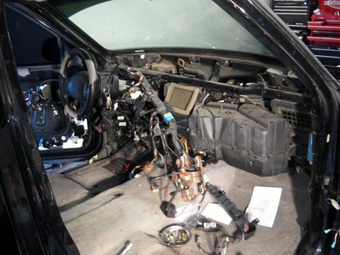 2007 Ford Mustang - The interior of a 2007 Ford Mustang is shown with its dashboard removed, revealing extensive wiring and internal components.