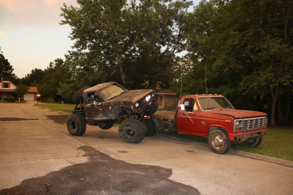 Red pickup truck towing a heavily modified off-road buggy with large tires