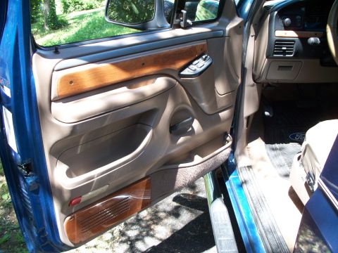 1995 Ford Bronco - Interior door panel of a 1995 Ford Bronco, showing wood trim and controls.