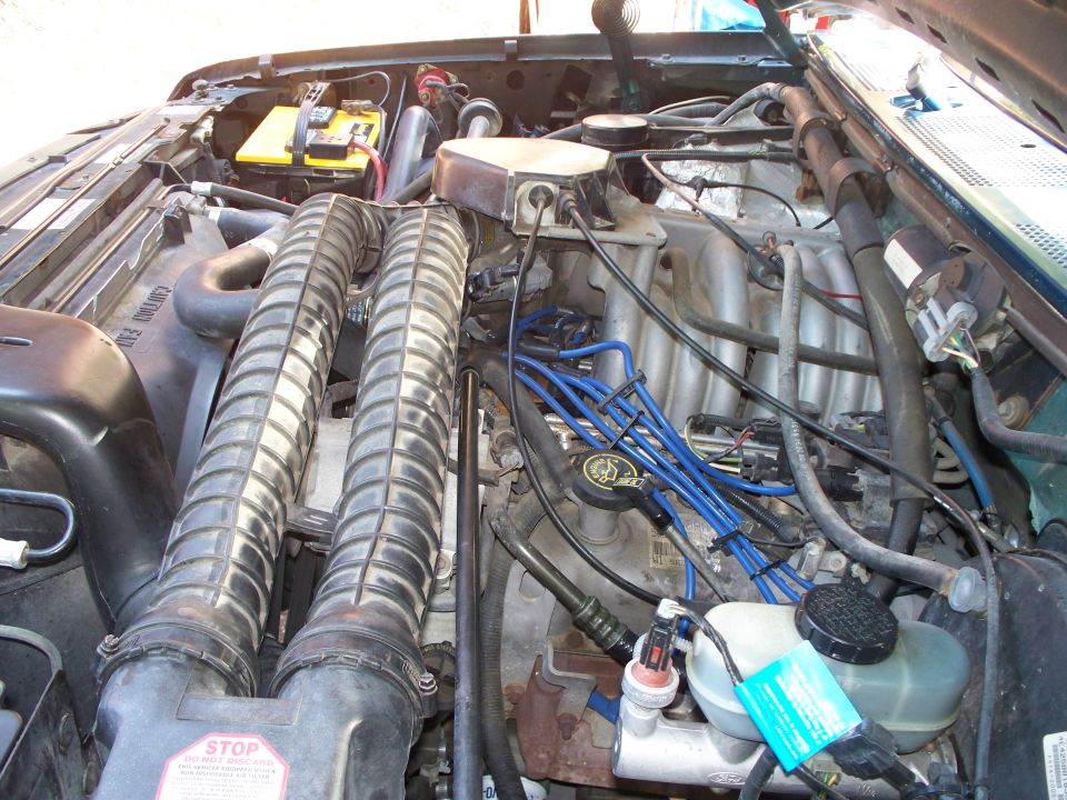 Engine bay with dual air intake tubes, battery, and various hoses and wires
