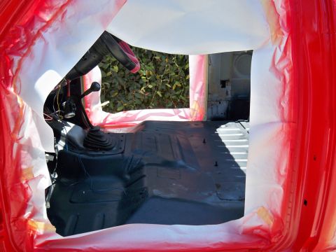 1985 Ford Bronco - The interior of a vehicle is shown with the floor coated in black paint, ready for further work.