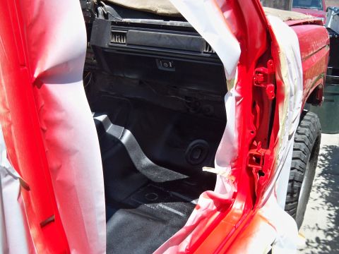 1985 Ford Bronco - The interior of a vehicle is being prepped for paint, with doors open and masking applied.