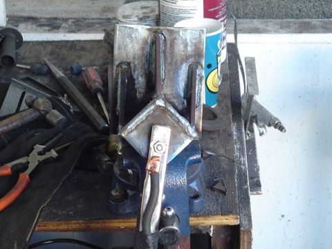 1993 Ford Bronco - Metal bracket being worked on in a vise, surrounded by tools on a workbench.