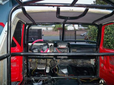 1985 Ford Bronco - The interior of a 1985 Ford Bronco shows a roll cage and unfinished wiring, suggesting a rebuild or modification project.