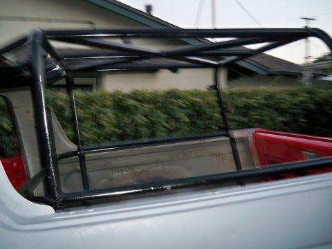1985 Ford Bronco - Roll cage installed in the bed of a pickup truck, showing the red interior of the bed.
