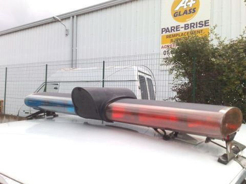 1991 Ford Crown Victoria - Light bar on top of a vehicle, with a building and fence in the background.
