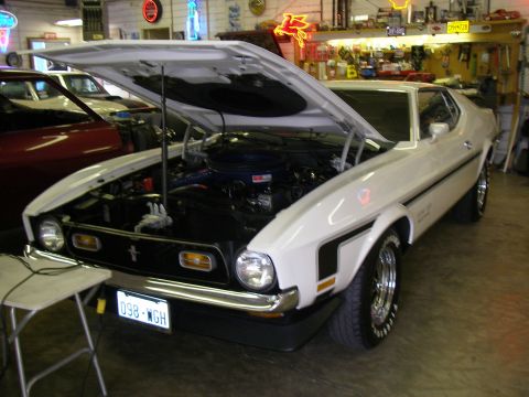 1971 Ford Mustang - A white 1971 Ford Mustang Mach 1 is parked in a garage with its hood open, revealing the engine bay.