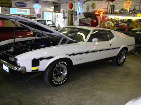 1971 Ford Mustang - A white 1971 Ford Mustang Boss 351 is parked in a garage with its hood up, showing the engine.