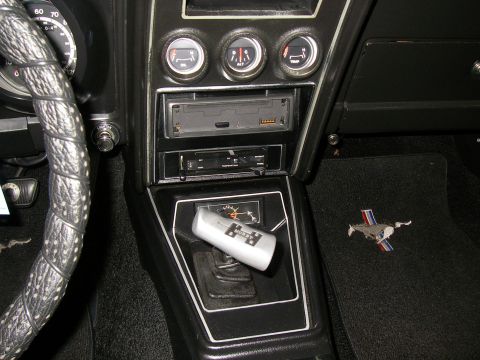 1971 Ford Mustang - The interior of a 1971 Ford Mustang features a dashboard with gauges, a radio, and a floor mat with the iconic running horse emblem.