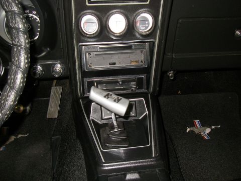 1971 Ford Mustang - The interior of a 1971 Ford Mustang, the iconic pony emblem on the floor mat and a close-up of the shifter and dashboard gauges.