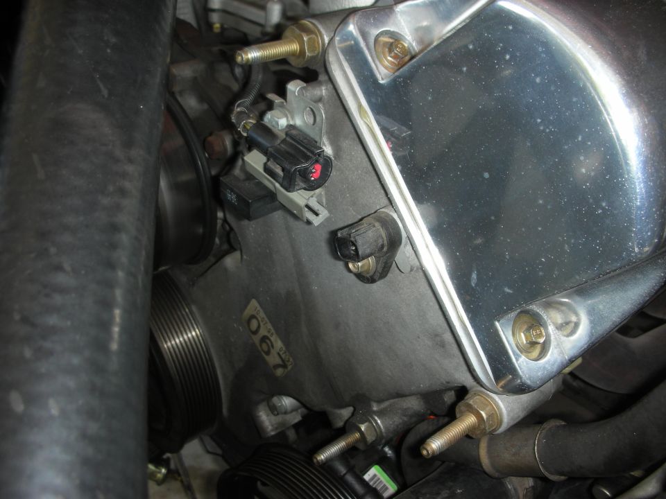 Engine block with sensors, pulley, and chrome cover. Part number 067 visible