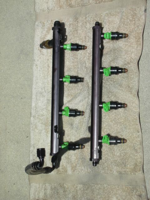 1992 Ford Crown Victoria - Two fuel injector rails with multiple green fuel injectors are laid out on a towel.