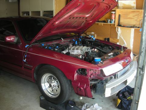 1992 Ford Crown Victoria - A maroon 1992 Ford Crown Victoria is shown with its hood up and the front end disassembled, revealing the engine bay.
