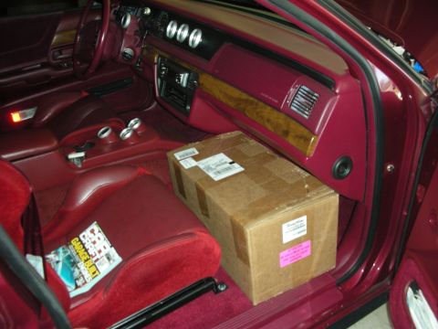 1992 Ford Crown Victoria - A box is placed on the passenger seat of a car, with a magazine visible on the driver's seat.