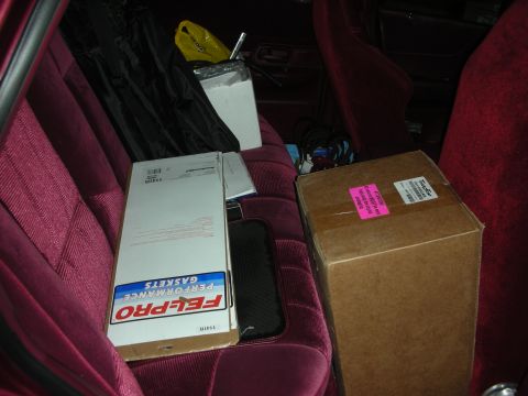 1992 Ford Crown Victoria - Boxes and car parts are visible on the burgundy seats inside a vehicle.