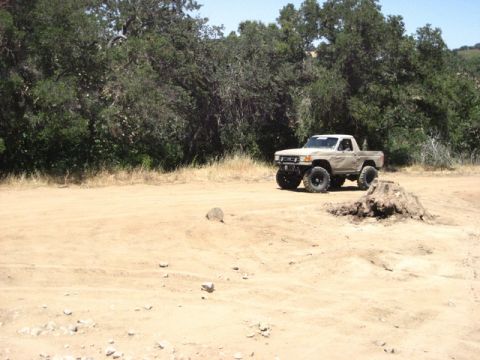 1989 Ford Bronco - This tan pickup truck is equipped with large off-road tires, suggesting it is used for trail driving.