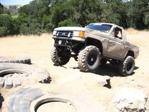 1989 Ford Bronco - Modified 1989 Ford Bronco tackling rough terrain with oversized tires.