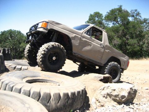 1989 Ford Bronco - This heavily modified truck navigates a challenging off-road course with large tires and a lifted suspension.